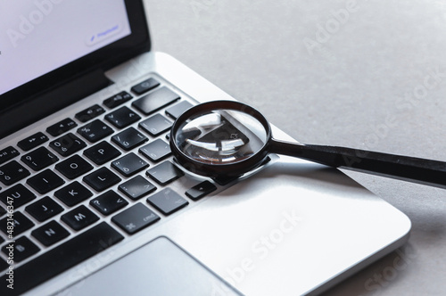 Laptop computer with magnifying glass, concept of search. 