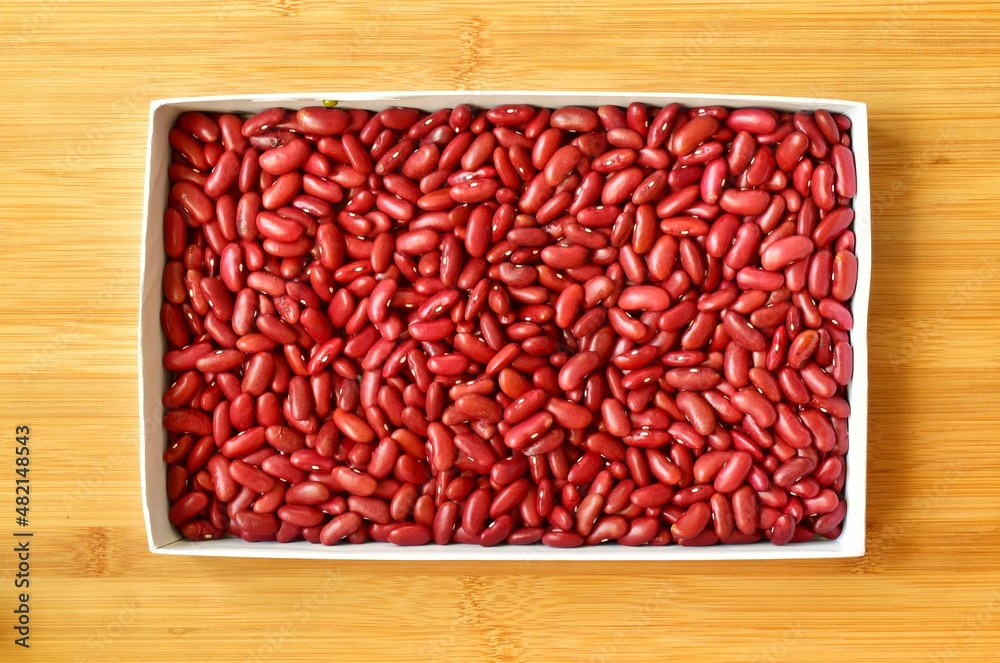 Red beans in a white square paper box on a wooden board background. Red beans in a white square paper box on a wooden board background.