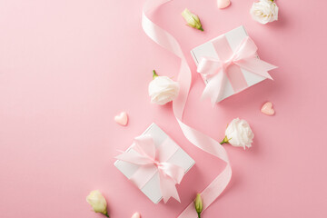 Top view photo of woman's day composition white gift boxes with pink bows curly silk ribbon small hearts and white prairie gentian flower buds on isolated pastel pink background with copyspace