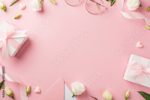 Top view photo of woman's day composition gift boxes pink ribbon envelope with letter stylish glasses hearts and prairie gentian flowers on isolated pastel pink background with copyspace in the middle © ActionGP