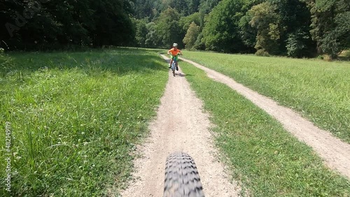Cute little boy riding a bike.	 

Boy riding a bike along the cycle path. Stabilized video.