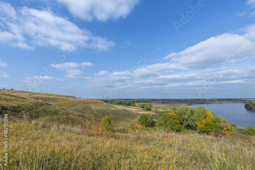 Autumn landscape with a view of the river and endless expanses of fields. Panoramic landscape with river and field and trees.