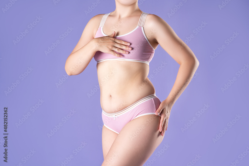 Fat woman in pink underwear on purple background, overweight female body