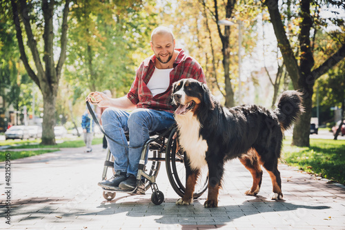 Happy young man with a physical disability who uses wheelchair with his dog.
