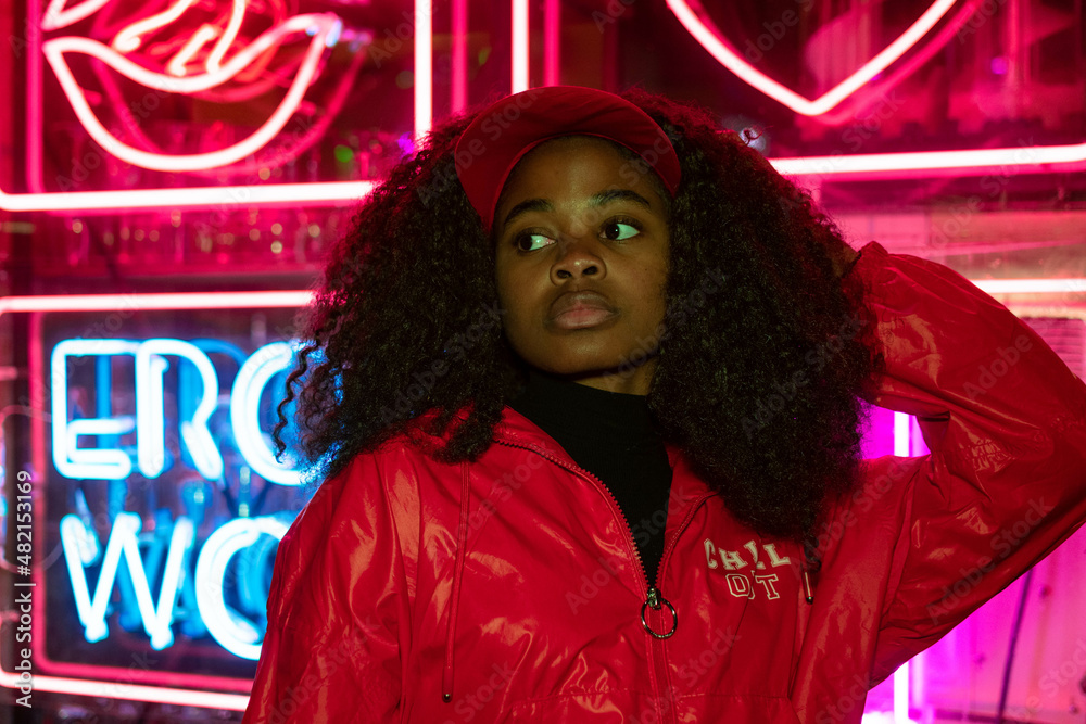 Fototapeta premium portrait of an African American young woman in sunglasses isolated on a neon light background 