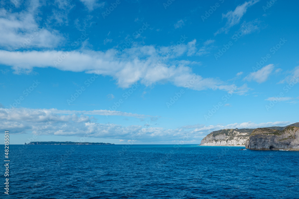 クルーズ船から見た新島の白ママ断崖と遠くに見える式根島