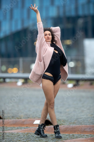 A girl with long legs in trendy fishnet stockings, and black shoes against the backdrop of the city photo