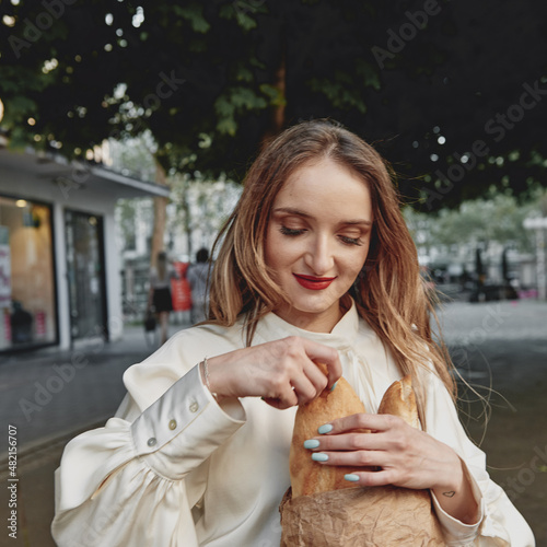 girl walks around the city French baguette in her hands
