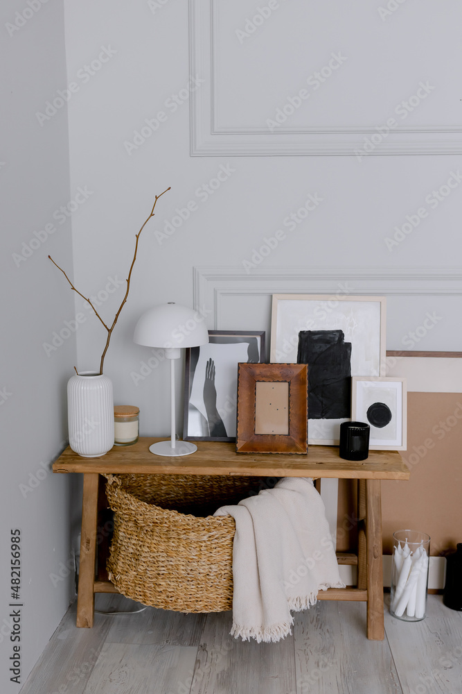 Obraz premium Wooden bench in the room Scandinavian style interior accessories Lamp and vase with photo frames Wicker basket with plaid for decor