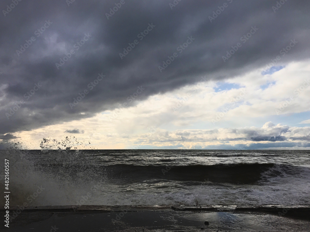 A large wave broke crashing into a breakwater. Storm landscape of Black Sea coast. Nature, environment, ecology, meteorology, fickle weather. Broken and blurry after hitting a concrete breakwater prot