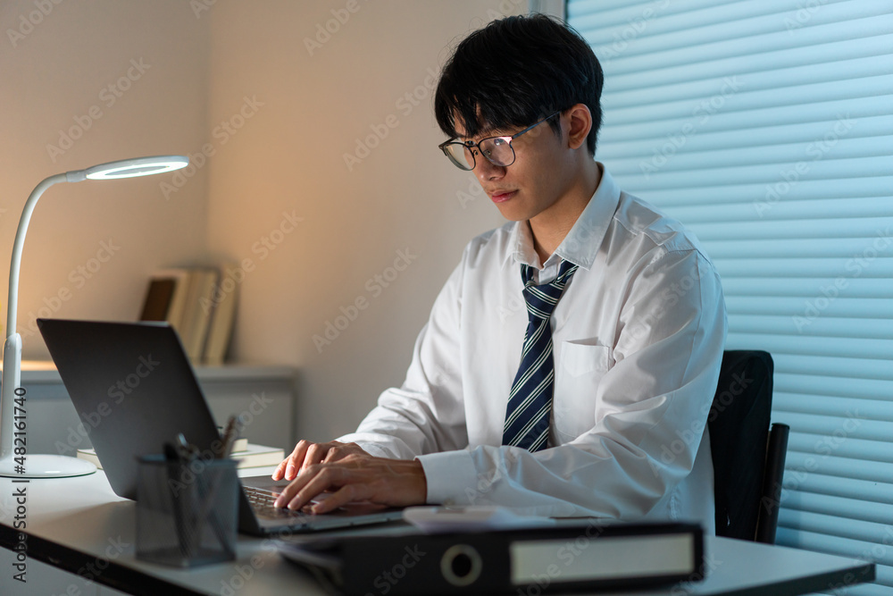 Overwork Concept The man sitting at his desk and focusing on working through his computer laptop Overwork Concept The man sitting at his desk and focusing on working through his computer laptop