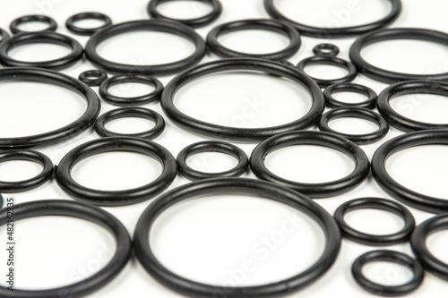 Background of o-rings and gaskets in black on a white background. Hydraulic and pneumatic o-rings in black in different sizes on a white background. Various seals for plumbing. 