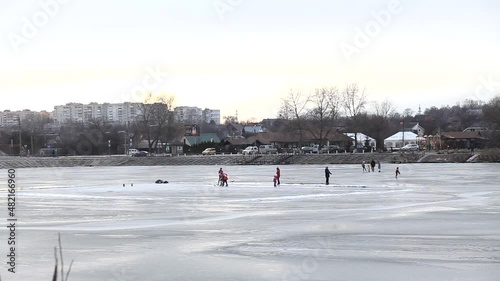People walk on the frozen lake in winter. Leisure and health improvement in winter, winter outdoor games. Two hockey players train outdoors in winter on the ice of a frozen lake.