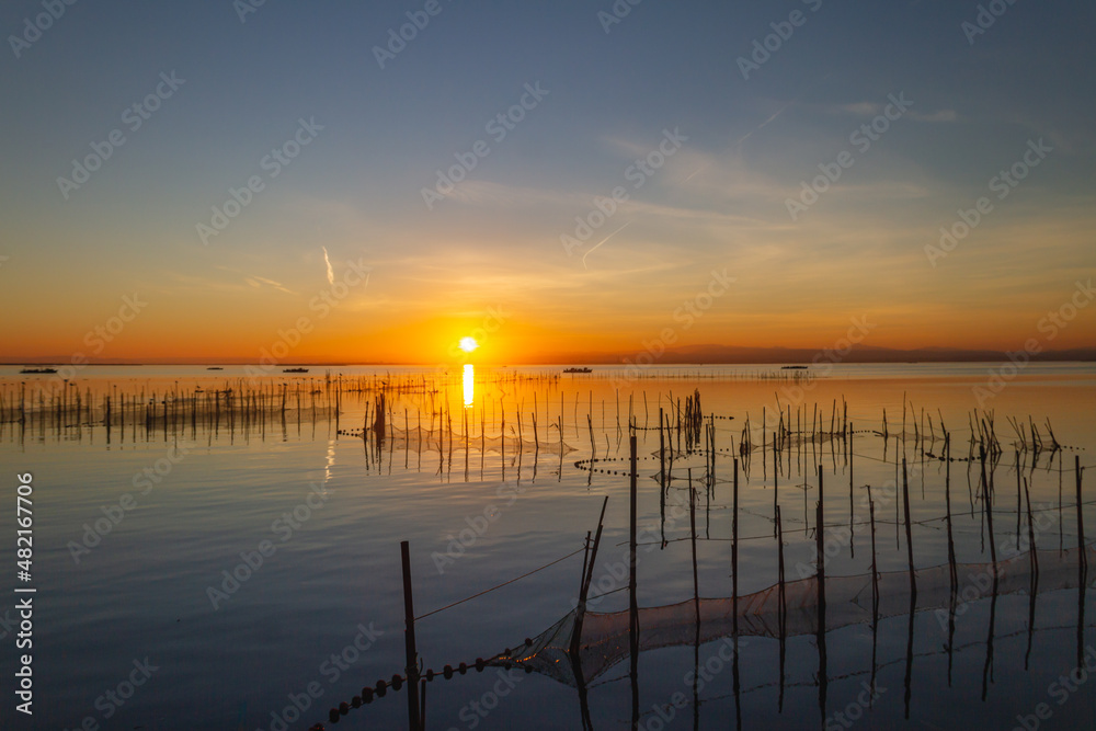 Landscape of La Albufera de Valencia in Spain at sunset with fishing nets in the foreground