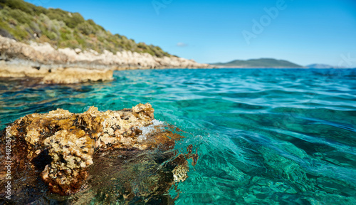 Close up clear blue sea or ocean water surface and coastal sea rocks beach