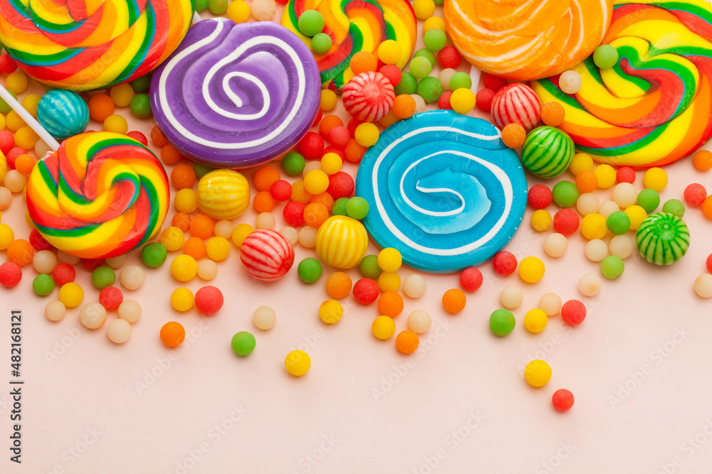 colorful lollipops and round candies on pink background. Top view.