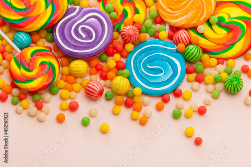 colorful lollipops and round candies on pink background. Top view.