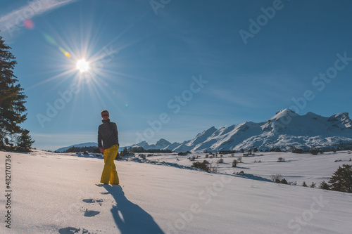 A full-body shot of a young Caucasian woman walking towards the camera in the French Alps mountains (La Joue du Loup, Devoluy)