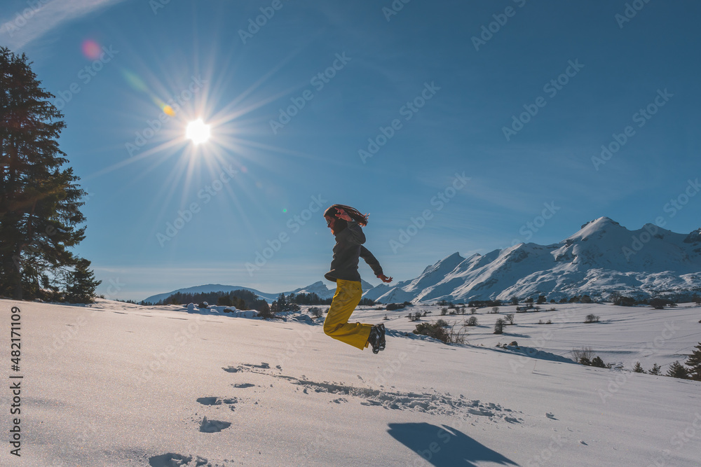 A full-body shot of an unrecognizable playful young Caucasian woman jumping in the French Alps mountains (La Joue du Loup, Devoluy)