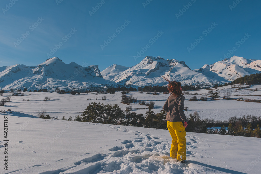 A full-body shot of an unrecognizable playful young Caucasian woman jumping in the French Alps mountains (La Joue du Loup, Devoluy)