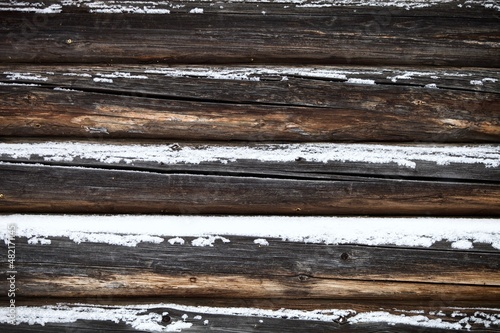 weathered surface of the old wooden log house wall close-up. log walls texture close up. Wooden Log cabin wall in snow close up. The frame of a wooden blockhouse. Vintage log wall surface full frame.