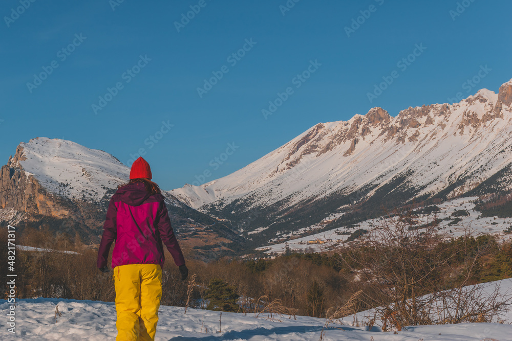 A full-body shot of an unrecognizable young Caucasian woman walking in the French Alps mountains (La Joue du Loup, Devoluy)