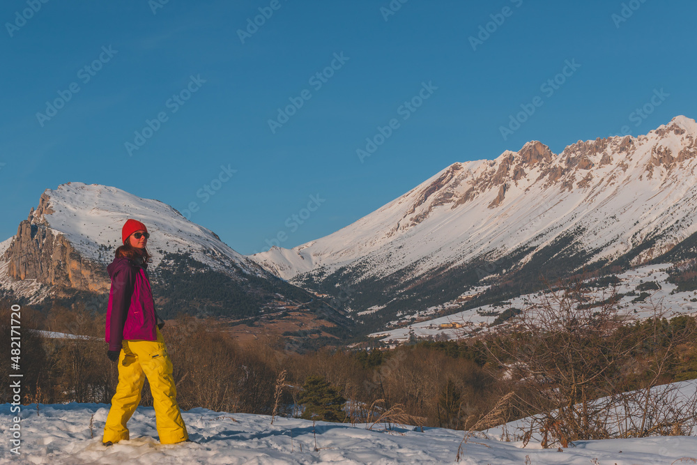 A full-body shot of a young Caucasian woman standing in the French Alps mountains (La Joue du Loup, Devoluy)