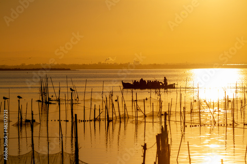 Traditional boat from the Albufera lake of Valencia in Spain transports tourists to observe the beauty of the sunset in the golden hour