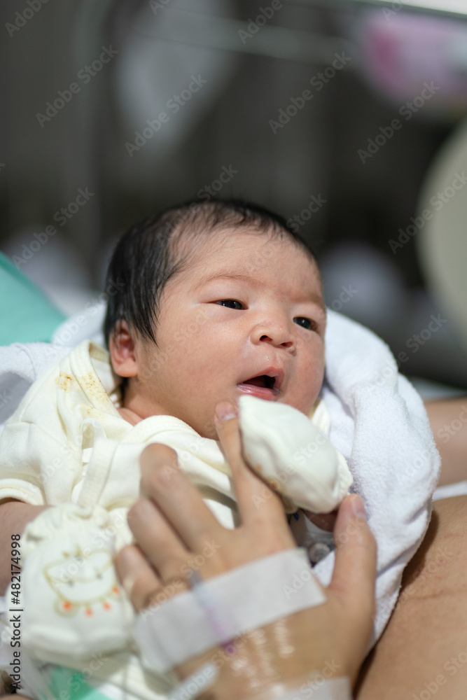 Cute infant Caucasian newborn baby which is sleeping on mother's embrace, baby portrait close-up photo.	
