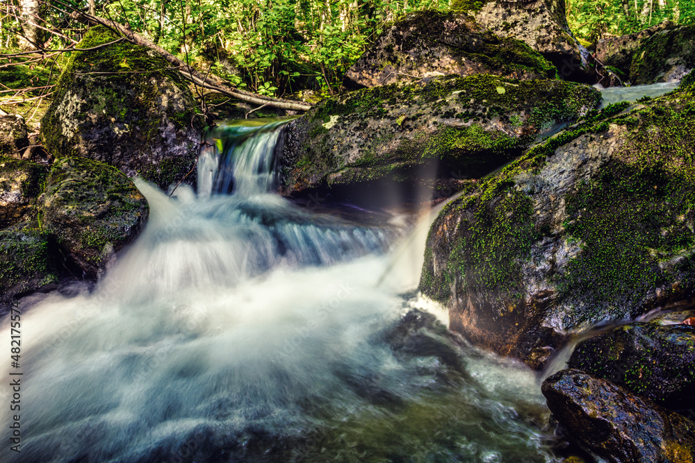 Naklejka premium Beautiful river with flowing water, rapids, rocks moss and forest in background, long exposure in volda, norway