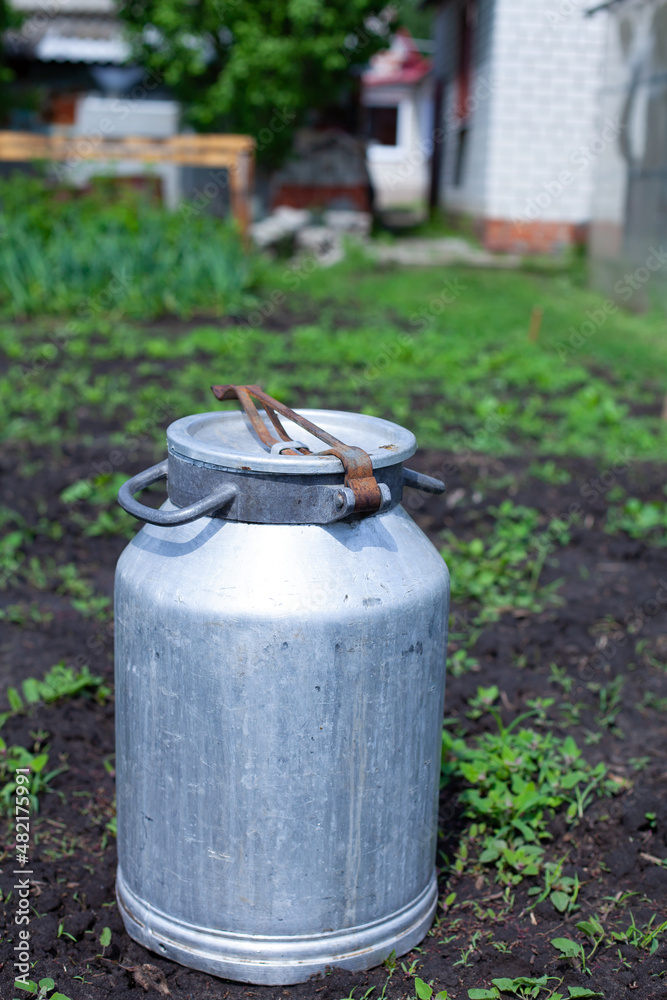large vertical photo. summer time. aluminum jar in the middle of the garden. environmentally friendly materials on the farm. metal barrel for liquid products. large vertical photo. summer time. aluminum jar in the middle of the garden. environmentally friendly materials on the farm. metal barrel for liquid products.