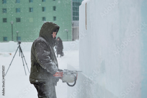 Worker cuts ice panel with gasoline saw