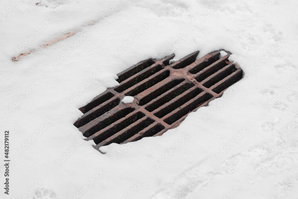 Drainage drain on the road covered with snow