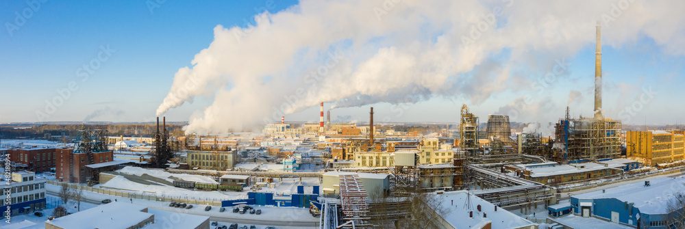 Industrial landscape. Panoramic view of the technological pipe and industrial infrastructure. Chemical production with red-white pipes and smoke is coming. Production buildings. Industrial landscape. Panoramic view of the technological pipe and industrial infrastructure. Chemical production with red-white pipes and smoke is coming. Production buildings.