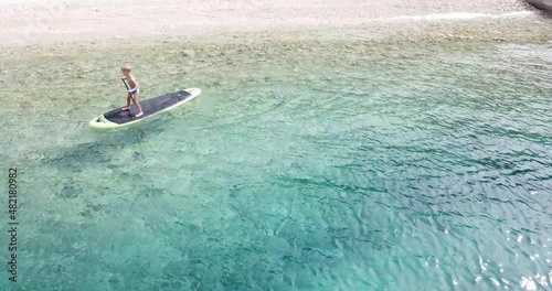 Little boy on a paddleboard.
Cute child learning on a paddleboard. Aerial view.