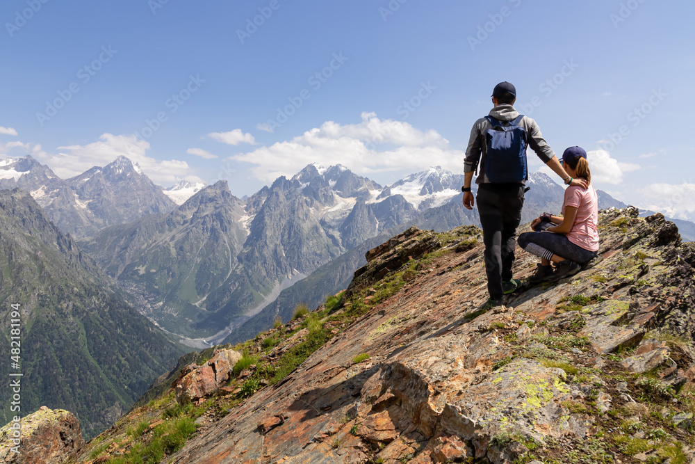 A hiking couple enjoying the amazing views on the mountain ridges in the Greater Caucasus Mountain Range in Georgia, Samegrelo-Upper Svaneti Region. Freedom. Wanderlust. Trekking to Koruldi Lakes