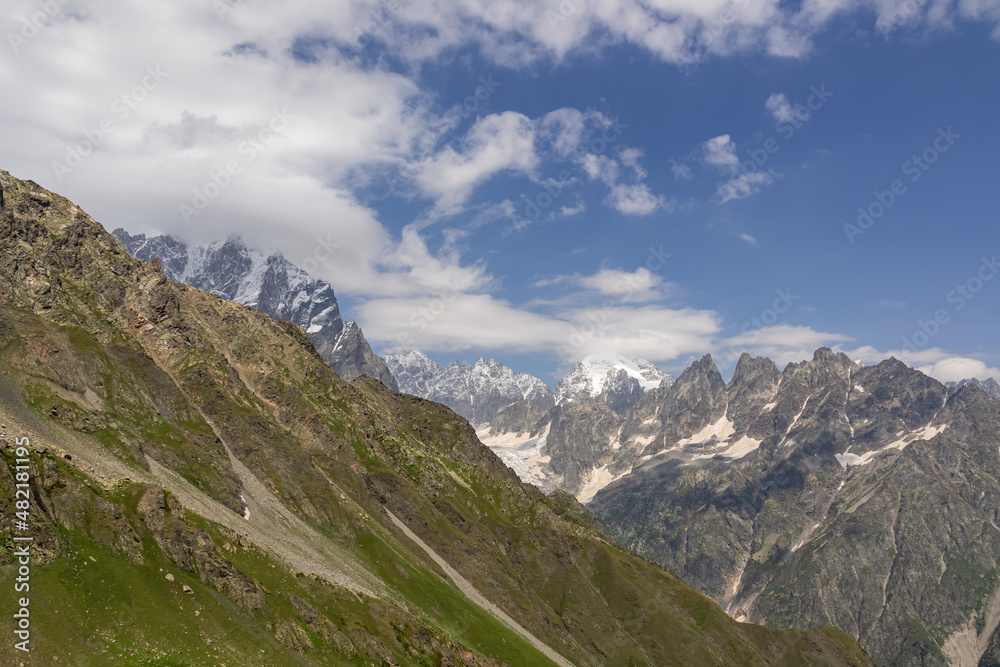An amazing panoramic view on the mountain ridges near Mestia in the Greater Caucasus Mountain Range, Samegrelo-Upper Svaneti, Country of Georgia. The sharp peaks are covered in snow. Clouds arriving