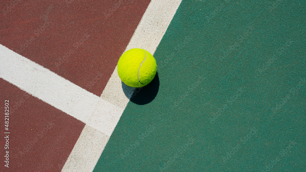 Yellow tennis ball lying on line of the red and green court. Flat lay view. Space for text