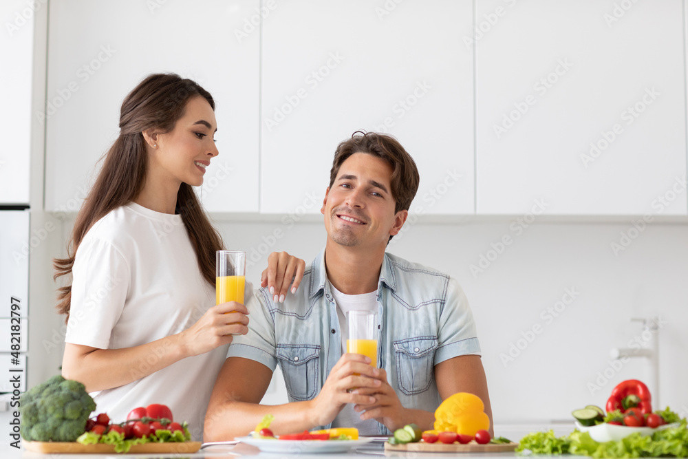 Portrait of a young healthy couple in love with juice in their hands in the kitchen, vegetarian nutrition. Portrait of a young healthy couple in love with juice in their hands in the kitchen, vegetarian nutrition.