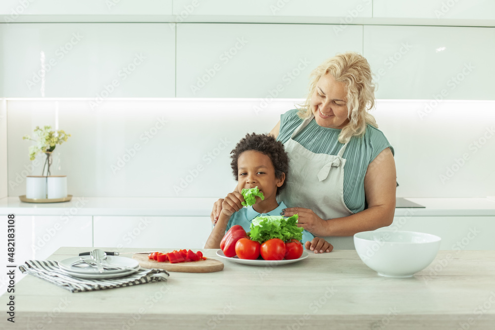 Joyful boy and his mother in aprons laughing in kitchen Joyful boy and his mother in aprons laughing in kitchen