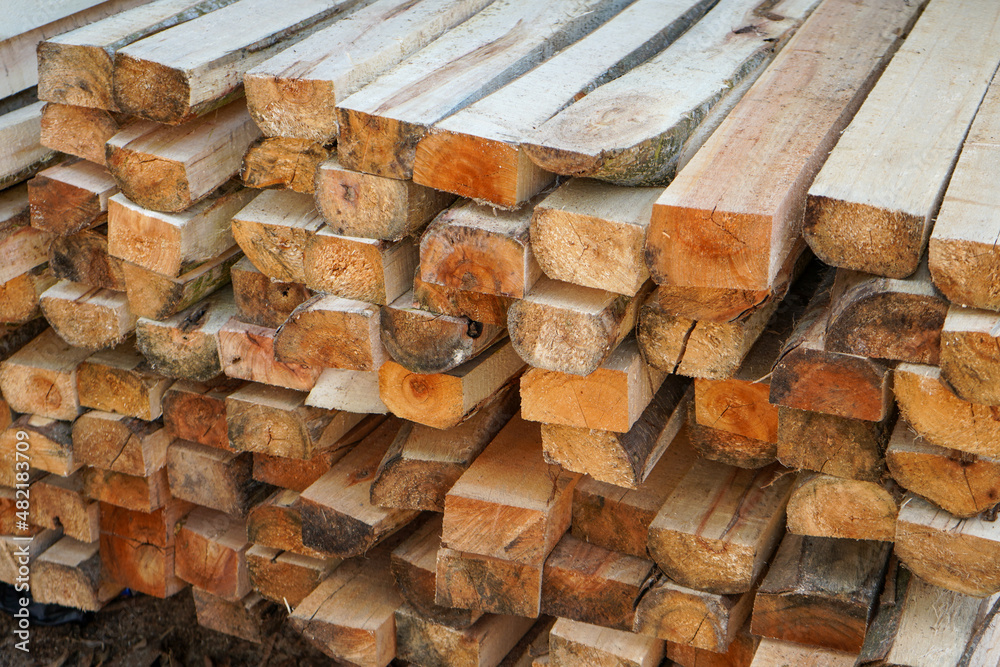 Piles of wood from logging forests to be used as raw materials for furniture. Piles of round and square wood form patterns and textures. Piles of wood from logging forests to be used as raw materials for furniture. Piles of round and square wood form patterns and textures.