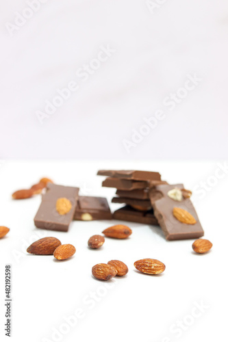 chocolate bars with peanuts, almonds and dried beans on a white background