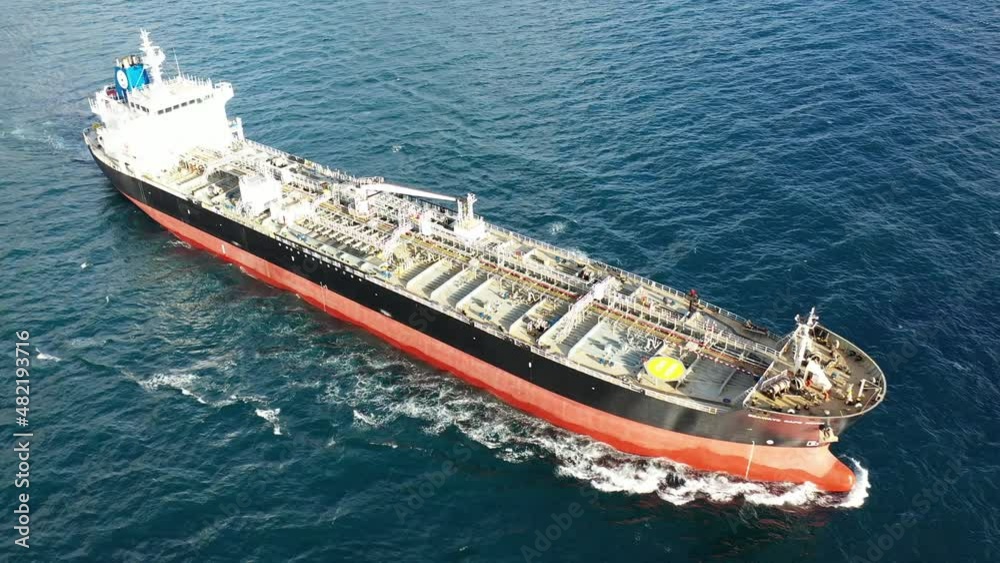 Aerial top down tracking video of industrial crude oil tanker cruising deep blue open ocean sea Aerial top down tracking video of industrial crude oil tanker cruising deep blue open ocean sea