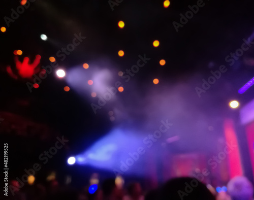 Defocused abstract blurred scene of musical light performance in a concert on stage with crowd