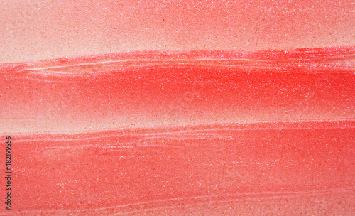 Texture of pink peach color textured lip gloss smear as background close view photo