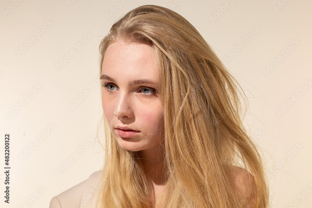 Naklejka premium Young woman with blonde hair isolated on beige portrait with nude make-up