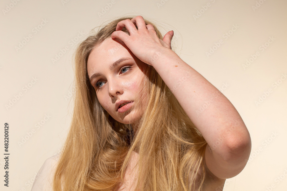 White young woman with blonde hair isolated on beige portrait with nude make-up White young woman with blonde hair isolated on beige portrait with nude make-up