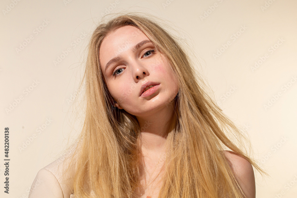 Naklejka premium White young woman with blonde hair isolated on beige portrait