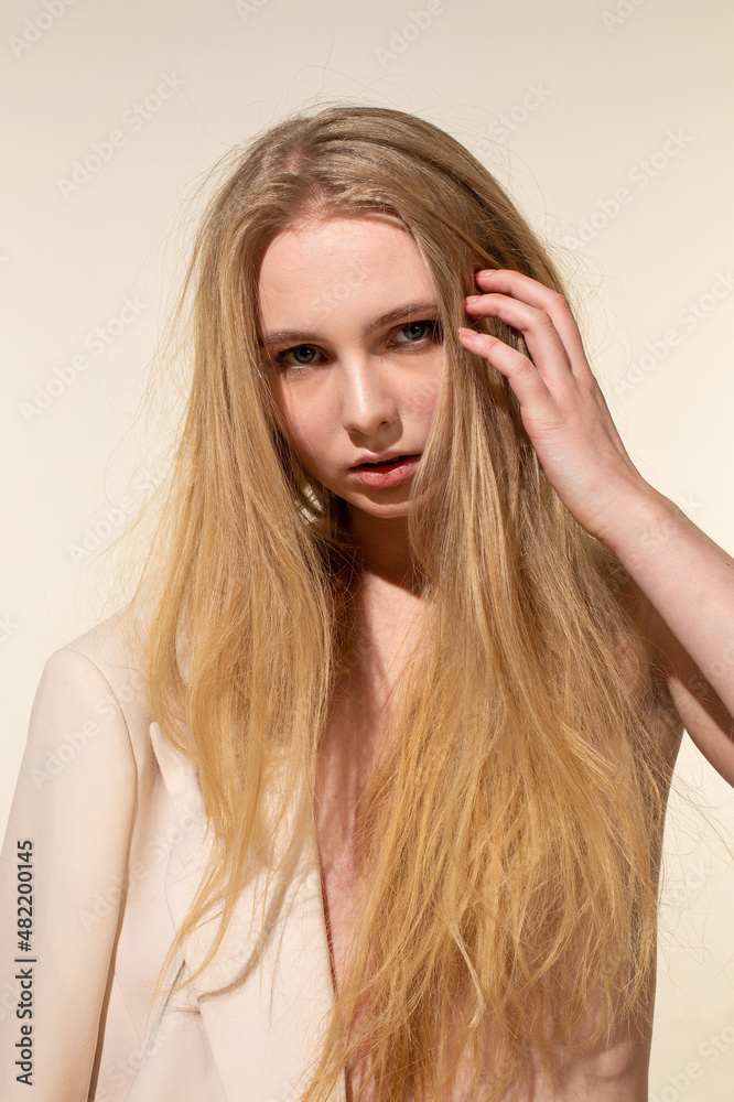 European young woman with blonde hair isolated on beige with hand near the face European young woman with blonde hair isolated on beige with hand near the face