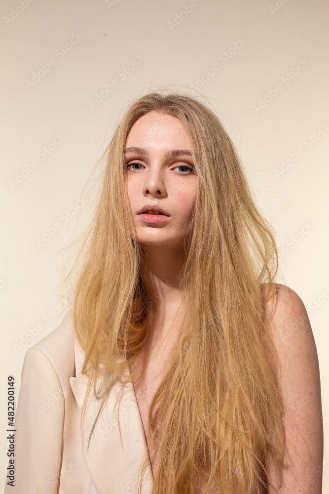 Naklejka premium White young woman with blonde hair isolated on beige in beige blazer
